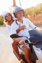 Mature Couple Riding Motor Scooter Along Country Road Royalty Free Stock Photo
