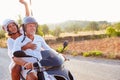 Mature Couple Riding Motor Scooter Along Country Road Royalty Free Stock Photo