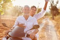 Mature Couple Riding Motor Scooter Along Country Road Royalty Free Stock Photo