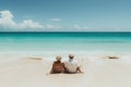 Mature couple sitting at the beach edge, waves gently touching their feet, in a peaceful embrace Royalty Free Stock Photo