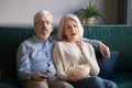 Mature couple sitting on couch watching drama movie Royalty Free Stock Photo