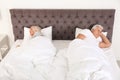 Mature couple sleeping back to back in bed at home.