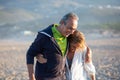 Mature couple in sportswear hugging while walking along shore Royalty Free Stock Photo