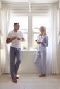 Mature Couple Standing By Bedroom Window With Hot Drink Royalty Free Stock Photo