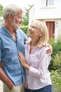 Mature Couple Standing In Garden In Front Of Dream Home In Countryside