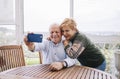 A mature couple takes a selfie with their mobile phone on the terrace of their house