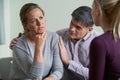 Mature Couple Talking With Counsellor As Man Comforts Woman