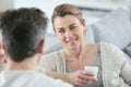 Mature couple talking to eachother at home and drinking coffee