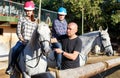 Mature couple with trainer riding horse at farm outdoor Royalty Free Stock Photo