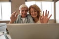 Mature couple wave hands at video call on laptop Royalty Free Stock Photo