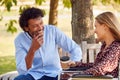 Mature Couple With Woman Sitting In Wheelchair Talking And Drinking Coffee In Park Together Royalty Free Stock Photo