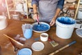 Mature craftswoman painting a plate made of clay in art studio