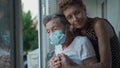 Mature daughter visiting senior mom in nursing home. Elderly daughter hugs her 90 year old mother in medical mask while Royalty Free Stock Photo