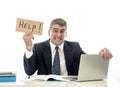 Mature desperate businessman suffering stress working at computer desk holding sign asking for help looking stressed overworked