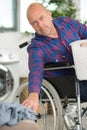 mature disabled man on wheelchair putting doing washing machie Royalty Free Stock Photo