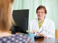 Mature doctor behind computer with patient Royalty Free Stock Photo