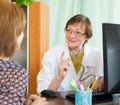 Mature doctor behind computer with patient Royalty Free Stock Photo