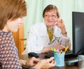 Mature doctor behind computer with patient Royalty Free Stock Photo
