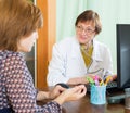 Mature doctor behind computer with patient Royalty Free Stock Photo