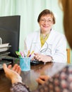 Mature doctor behind computer with patient Royalty Free Stock Photo