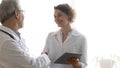 Mature doctor shaking smiling nurse hand, thanking for good work Royalty Free Stock Photo