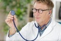 mature doctor holding up disc stethoscope Royalty Free Stock Photo