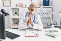 Mature doctor man at the clinic begging and praying with hands together with hope expression on face very emotional and worried Royalty Free Stock Photo