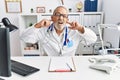 Mature doctor man at the clinic covering ears with fingers with annoyed expression for the noise of loud music Royalty Free Stock Photo