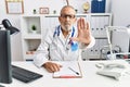 Mature doctor man at the clinic doing stop sing with palm of the hand Royalty Free Stock Photo