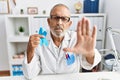 Mature doctor man holding blue ribbon at the clinic with open hand doing stop sign with serious and confident expression, defense Royalty Free Stock Photo