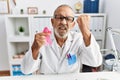 Mature doctor man holding pink cancer ribbon at the clinic annoyed and frustrated shouting with anger, yelling crazy with anger Royalty Free Stock Photo