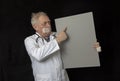 Mature doctor with tape across his mouth and pointing at a placard Royalty Free Stock Photo