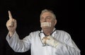 Mature doctor with tape across his mouth and pointing towards the sky Royalty Free Stock Photo