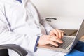 Mature doctor working on laptop and medication`s cases to make prescriptions in his clinic office. Man preparing online internet Royalty Free Stock Photo