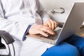 Mature doctor working on laptop and medication`s cases to make prescriptions in his clinic office. Man preparing online internet Royalty Free Stock Photo