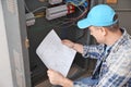 Mature electrician with circuit diagram near distribution board