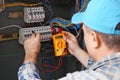 Mature electrician measuring voltage in distribution board