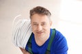 Mature electrician with wires on light background