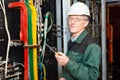 Mature electrician working in hard hat with cables Royalty Free Stock Photo