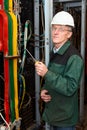 Mature electrician working in hard hat with cables Royalty Free Stock Photo