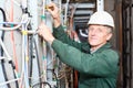 Mature electrician working in hard hat with cables Royalty Free Stock Photo