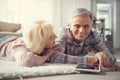 Mature enjoyed couple reposing on rug with device