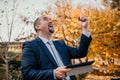 Mature business man in suit reading a news sitting in the park on the bench. Entrepreneur drink coffee in autumn park Royalty Free Stock Photo