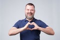 Mature european man with beard making out of the hands heart.