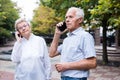 Mature european woman and man talking on the phone in summer park Royalty Free Stock Photo