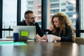 The mature executive is explaining project detail to permed hair female officer in the conference room. She is listening with an