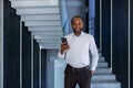 Mature experienced african american man inside office at workplace walking around office with phone in hand, portrait of Royalty Free Stock Photo