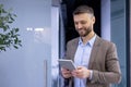 Mature experienced businessman inside office smiling contentedly, senior man holding tablet computer in hands, boss in Royalty Free Stock Photo