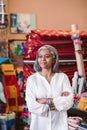 Mature fabric shop owner standing among her colorful textiles Royalty Free Stock Photo