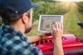 A mature farmer with tablet standing by mini tractor outdoors in orchard. Royalty Free Stock Photo
